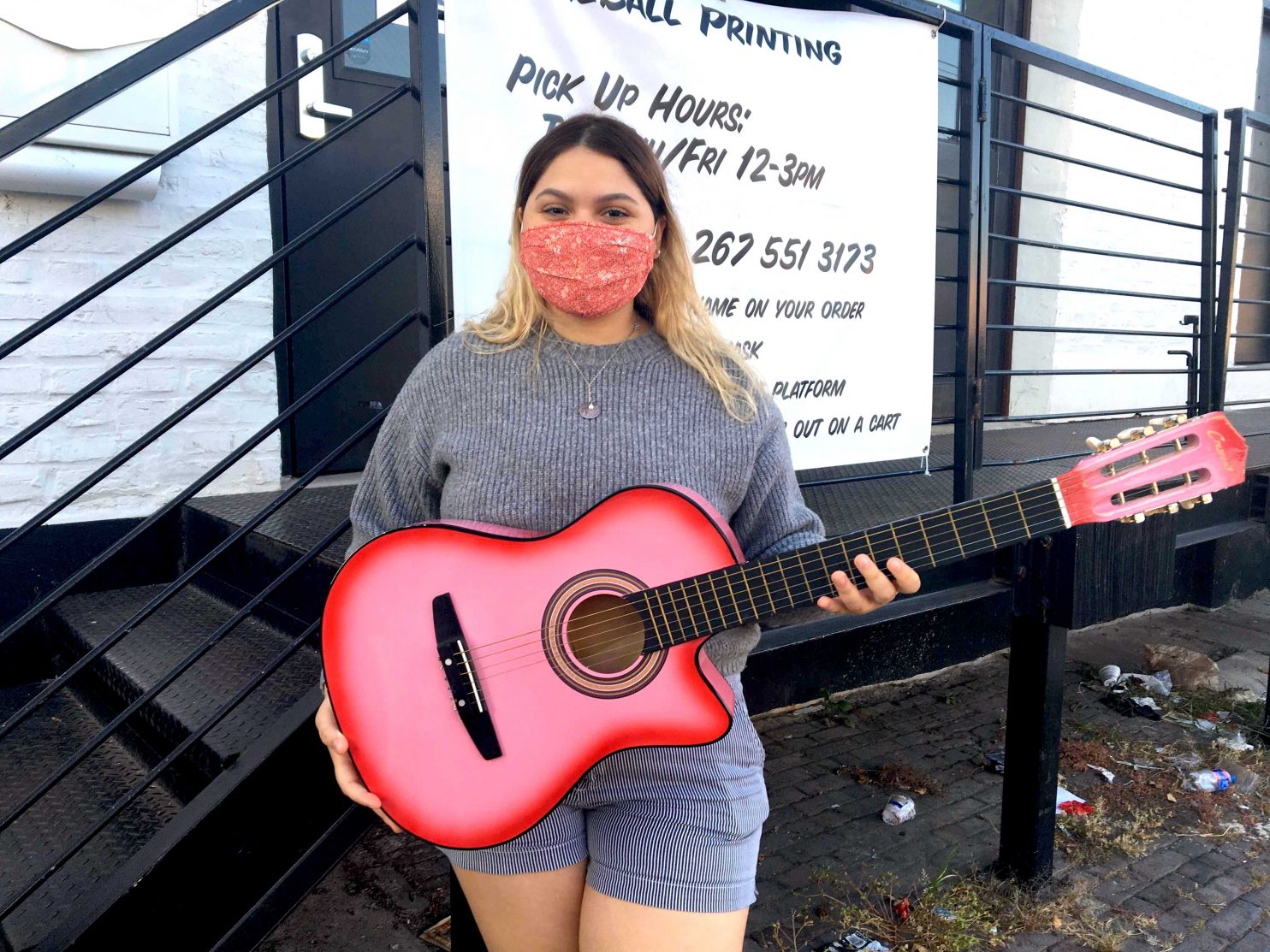 Teen holding a pink guitar with matching face mask